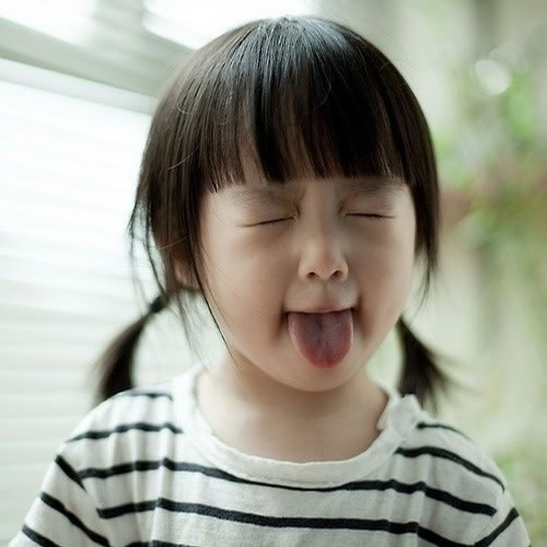 紧闭眼睛吐舌头的小女孩